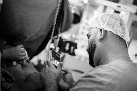 Profissional da saúde acompanhando o nascimento do bebê em sala cirúrgica, durante parto hospitalar.'