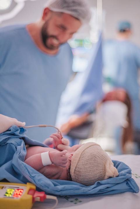Detalhe do procedimento realizado no recém-nascido logo após o nascimento, com acompanhamento da equipe médica.'