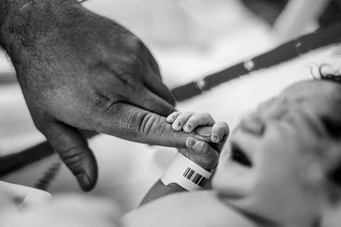 Profissional da saúde realizando procedimento de rotina no recém-nascido logo após o parto hospitalar.'