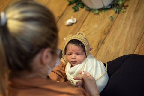 Priscilla Patzlaff, fotógrafa em Bento Gonçalves, ajustando o recém-nascido durante ensaio, sob orientação da mentoria newborn conduzida por Aline Fontes.'