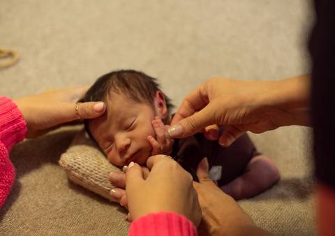 Aline Fontes orientando Priscilla Patzlaff Fotografias no manejo delicado do recém-nascido durante mentoria newborn em estúdio.'