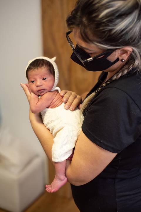 Recém-nascido sendo segurado com segurança durante mentoria newborn com Aline Fontes e Priscilla Patzlaff Fotografias, em estúdio em Bento Gonçalves.'