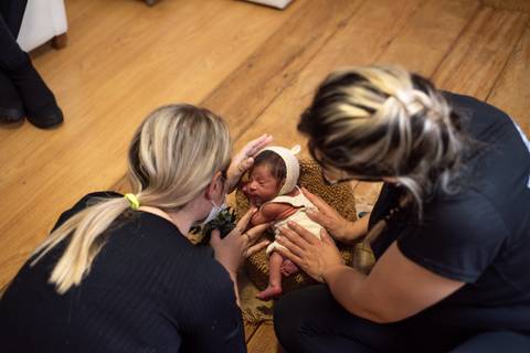 Aline Fontes orientando Priscilla Patzlaff, fotógrafa especialista em newborn, no manejo seguro do recém-nascido durante ensaio.'