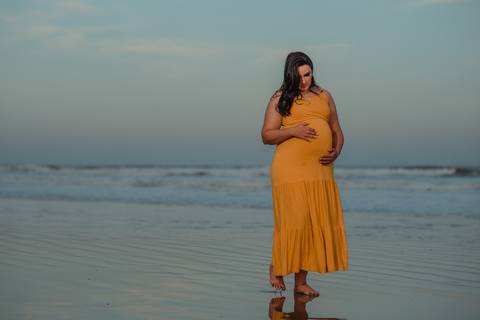 fotografia de gestante sozinha na praia ao pôr do sol
'