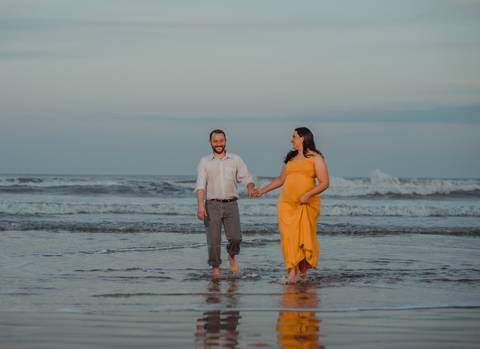 casal em ensaio gestante caminhando na beira do mar
'