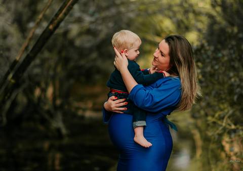 mãe grávida com filho no colo em ensaio externo'