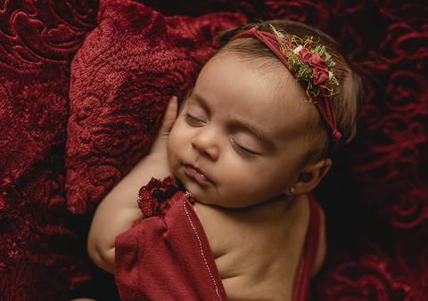 Ensaio old newborn com bebê de 45 dias em cenário vermelho, close delicado destacando traços do bebê'