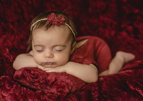 Bebê de 45 dias em ensaio old newborn, apoiada com os braços à frente, fotografia profissional em estúdio'