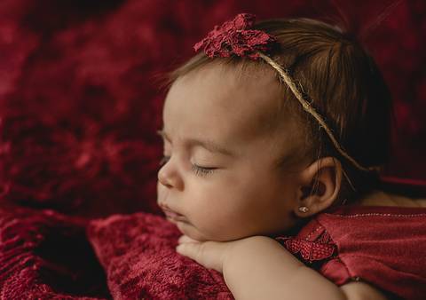 Ensaio old newborn com bebê de 45 dias em perfil, cenário vermelho e iluminação controlada, fotografia especializada'