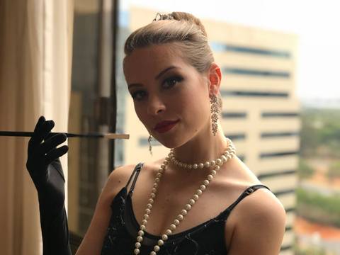 Jovem segurando piteira de cigarro fantasiada do personagem Bonequinha de Luxo.'