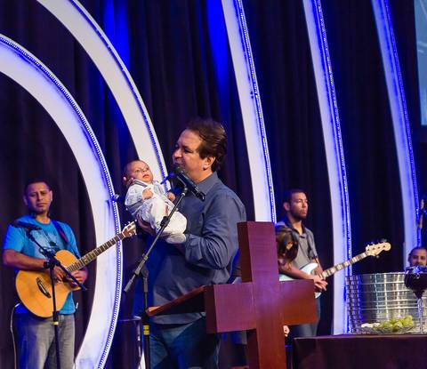 Pastor segura bebê para apresentação na Igreja Missão Praia da Costa pelo fotógrafo Douglas Maia'