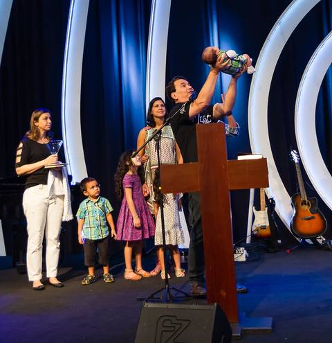 Pastor Simonton levanta criança consagrando-a a Deus na Igreja Missão Praia da Costa pelo fotógrafo Douglas Maia'