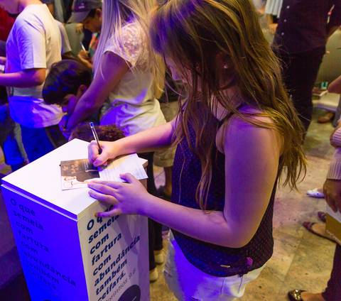 Mulher preenchendo papel na Igreja Missão Praia da Costa pelo fotógrafo Douglas Maia'
