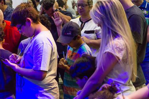 Fiéis preenchem papel na Igreja Missão Praia da Costa pelo fotógrafo Douglas Maia'