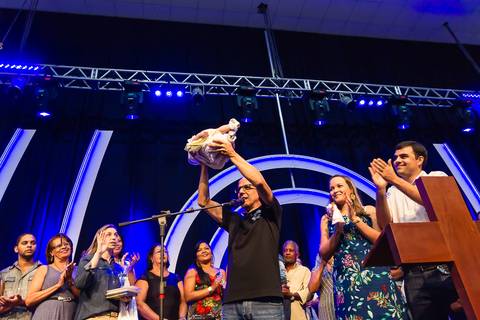 Pastor levanta criança e a apresenta a Deus na Igreja Missão Praia da Costa pelo fotógrafo Douglas Maia'