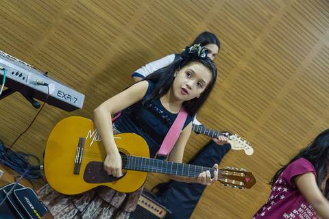 Menina tocando violão na Igreja Missão Praia da Costa pelo fotógrafo Douglas Maia'