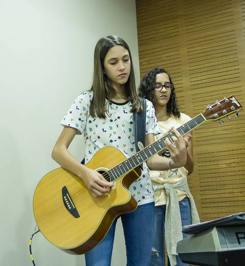 Menina tocando violão na Igreja Missão Praia da Costa pelo fotógrafo Douglas Maia'