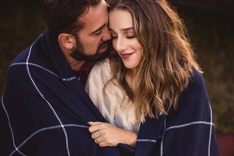 Retrato de casal abraçado carinhosamente com cobertor azul xadrez'
