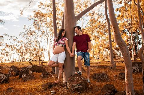 casal de mãos dadas sorrindo um para o outro em ensaio de gestante em maringa'