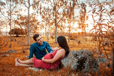 casal sentados na grama em ensaio de gestante em maringa'