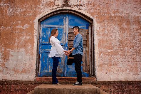 casal em frente a uma porta em um prédio abandonado em ensaio de gestante na regiao de maringa, igreja abandonada de mandaguari'