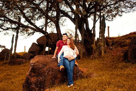 casal sentado em pedra olhando para horizonte na zona rural de mandaguari regiao de maringa em ensaio de gestante em maringa gravida'