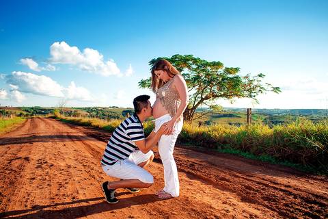 marido beijando barriga de esposa gravida em ensaio de gestante na estrada na zona rural de mandaguari regiao de maringa'