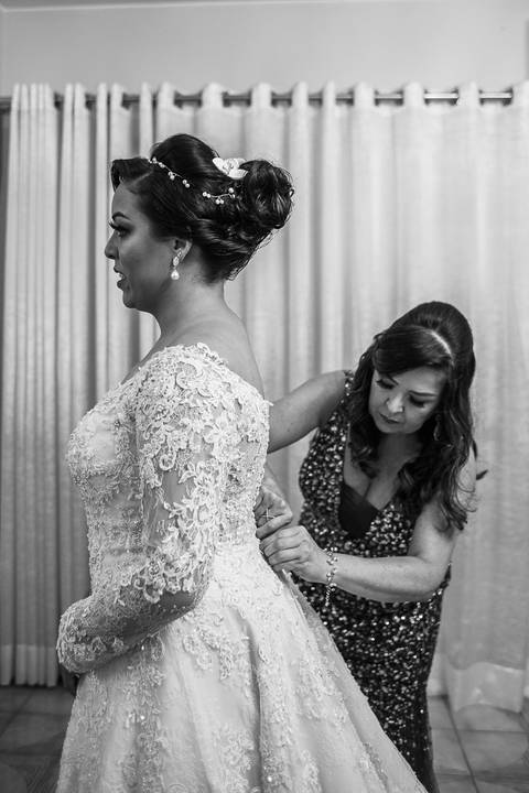 mae da noiva abotoando o vestido da filha'