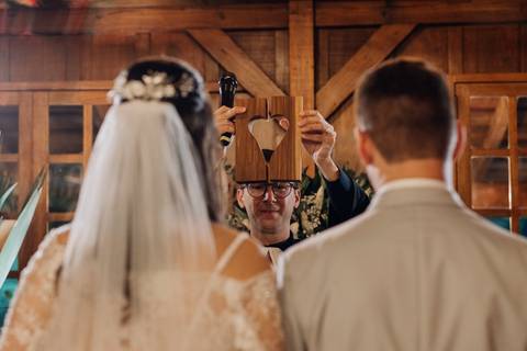 Celebrante segura peça com formato de coração durante cerimônia de casamento na Casa Irmando em Lajeado, foto por Alba Estúdio.'