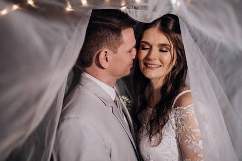 Noiva e noivo trocando carinhos sob o véu iluminado, em uma noite de casamento na Casa Irmando em Lajeado. Foto por Alba Estúdio.'