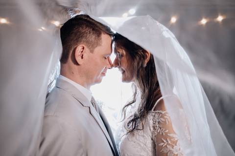 Noivos com os rostos colados sob o véu, trocando olhares apaixonados durante o casamento na Casa Irmando em Lajeado. Foto por Alba Estúdio.'
