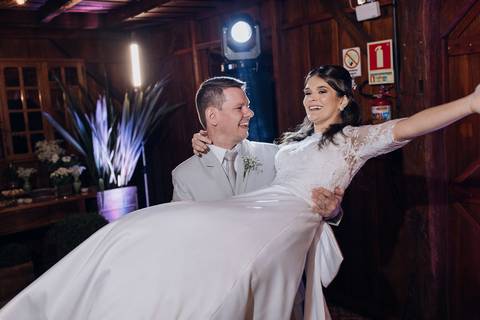 Noivo levanta a noiva sorridente durante a festa de casamento na Casa Irmando, em Lajeado. Foto por Alba Estúdio.'