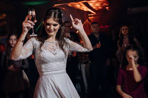 Noiva celebra com taça de espumante na pista de dança durante casamento na Casa Irmando, em Lajeado. Registro por Alba Estúdio.'