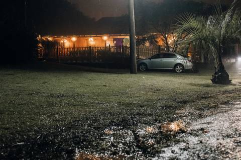 Fachada iluminada da Casa Irmando em noite de chuva durante festa de casamento em Lajeado. Foto de Alba Estúdio.'