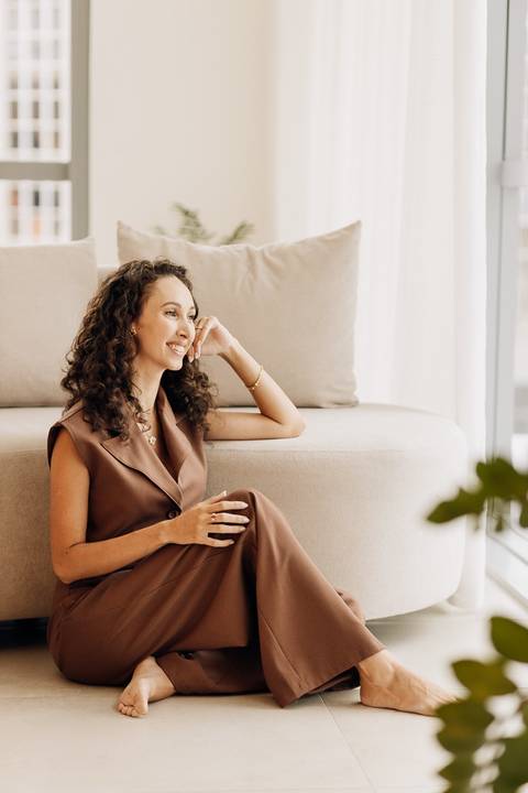 Close da psicóloga contemplativa junto ao sofá, ensaio de posicionamento de marca pessoal em ambiente clean no estúdio em Lajeado.'