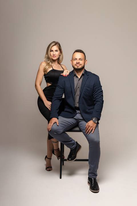 Michele apoia a mão no ombro de Vinícius enquanto posam para ensaio de estúdio'