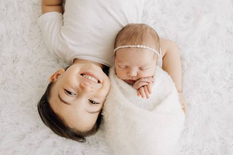 “Irmão mais velho beijando a testa da irmã recém-nascida”'