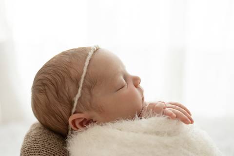 “Perfil do rosto da recém-nascida adormecida com headband de pérolas”'