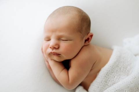 Close do bebê Lorenzo dormindo com os bracinhos cruzados sob o rosto, fundo branco, fotografia newborn no Alba Estúdio.'