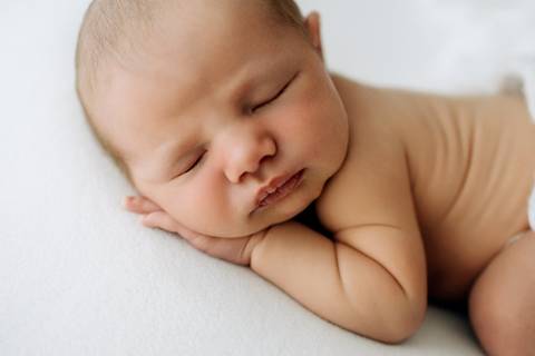Close newborn do bebê Lorenzo de perfil, dormindo com a mãozinha no rosto, fotografia no Alba Estúdio.'