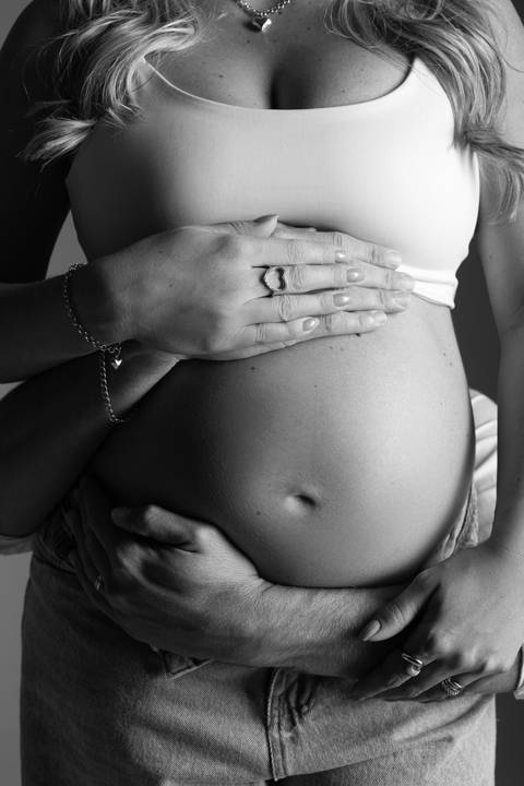 Detalhe em preto e branco da barriga de gestante envolvida pelas mãos do casal, destacando afeto, espera e conexão. Ensaio realizado pelo Alba Estúdio em Lajeado, RS.'
