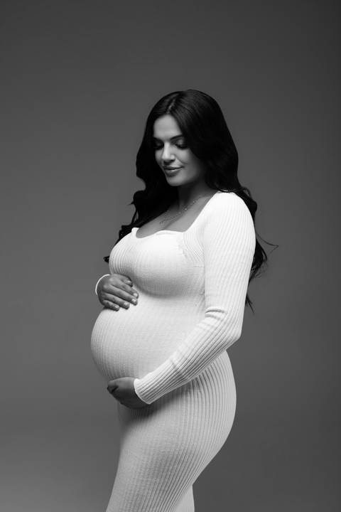 Retrato clássico em preto e branco de gestante com vestido branco, destacando delicadeza, elegância e conexão com o bebê. Alba Estúdio, Lajeado, RS.'