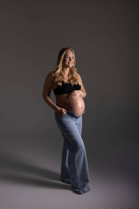 Retrato de gestante em estúdio com jeans e top preto, em uma proposta moderna, leve e elegante. Fotografia de gravidez do Alba Estúdio em Lajeado, RS.'