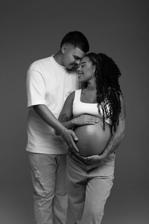 Retrato de casal durante ensaio gestante em estúdio, com composição em preto e branco e um momento delicado de carinho na espera por Maju. Fotografia do Alba Estúdio em Lajeado, RS.'