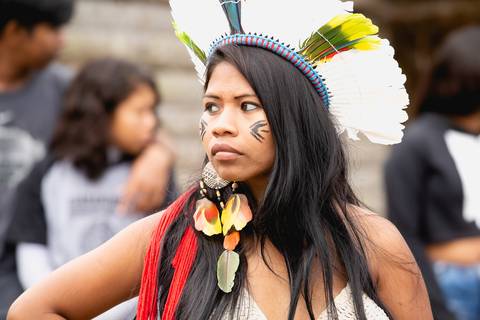 jovem índia com cocar é brinco de penas'