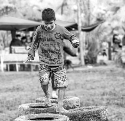 criança indígena brincando com pneus'