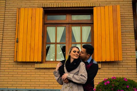 Noivos caminhando no passeio em campos do Jordão SP em frente a uma janela laranja foto ronny viana'