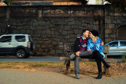 Casal fazendo carinho sentados em bando na cidade de campos do Jordão SP fotografia ronny viana fotografo de casamento em Piracicaba SP'