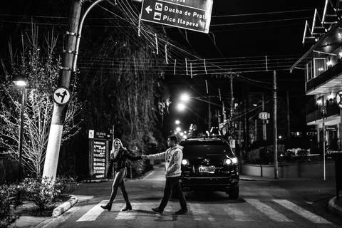 Atravessando a rua em campos do jordão a noite com frio e roupas de inverno fotografia ronny viana'