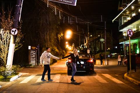 noivo com blusa branca de frio e calça preta em campos do jordão SP atravessando a rua '